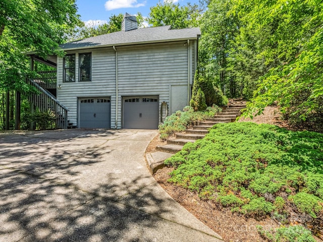 212 Ridgeway Rd, Lake Lure, NC 28746 - view of side of home with stairway, driveway, a garage, and a chimney