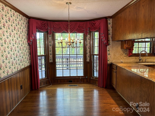 unfurnished dining area featuring a notable chandelier, a textured ceiling, sink, and dark wood-type flooring