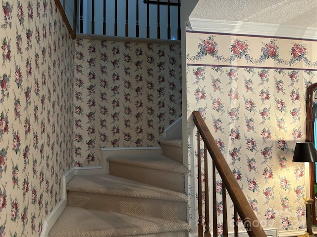 stairway featuring a textured ceiling and ornamental molding