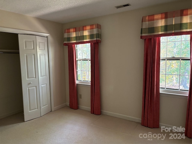 unfurnished bedroom featuring multiple windows, a closet, and light colored carpet