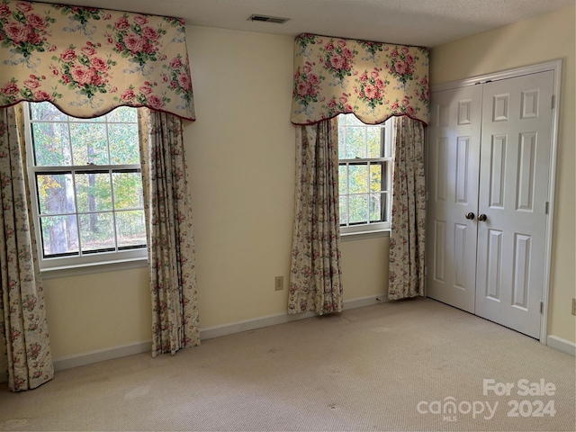 unfurnished bedroom with a textured ceiling, carpet floors, and a closet