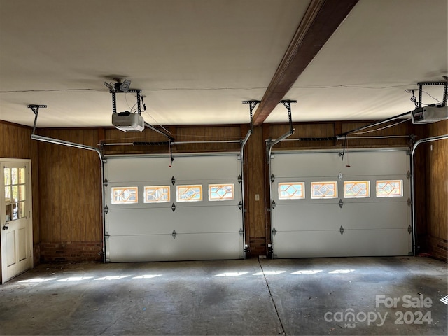 garage featuring a garage door opener and wooden walls