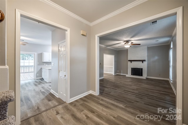 corridor featuring wood-type flooring, a textured ceiling, and ornamental molding