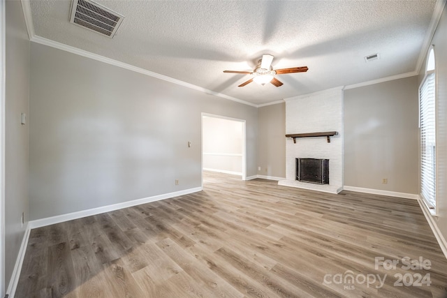 unfurnished living room with ceiling fan, ornamental molding, a brick fireplace, a textured ceiling, and hardwood / wood-style floors