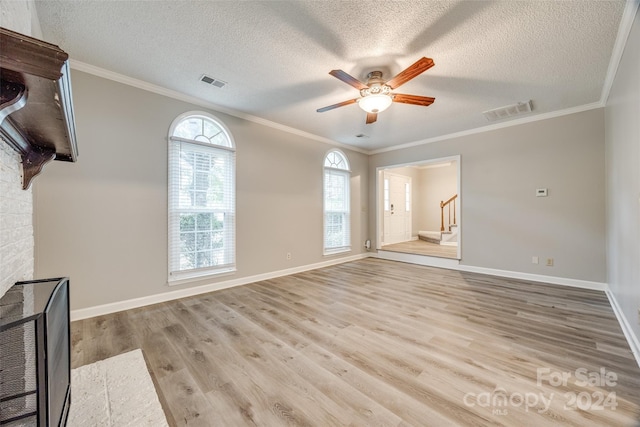 unfurnished living room with light wood-type flooring, a textured ceiling, ornamental molding, and ceiling fan