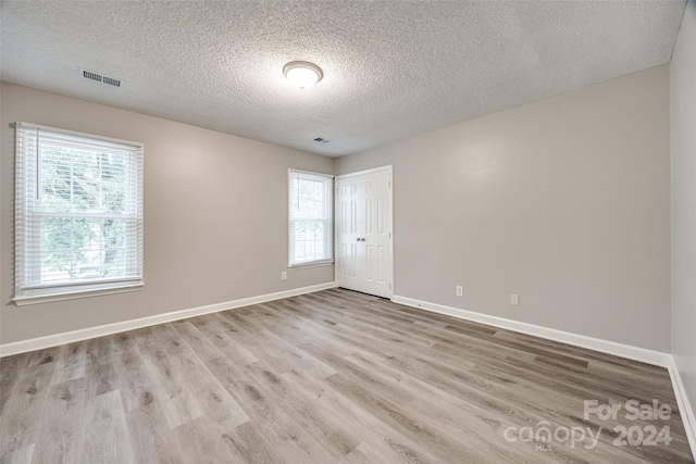 unfurnished room featuring light wood-type flooring and a textured ceiling