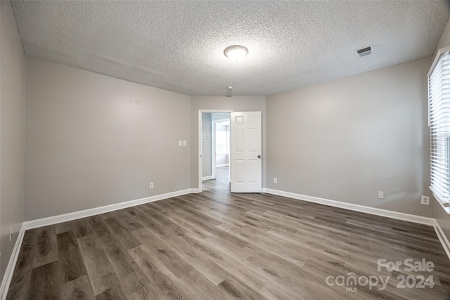 unfurnished room with a textured ceiling, dark hardwood / wood-style floors, and plenty of natural light