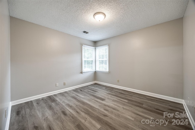 empty room featuring a textured ceiling and dark wood-type flooring