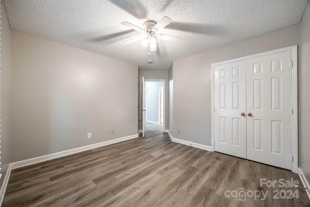 unfurnished bedroom with a closet, ceiling fan, hardwood / wood-style flooring, and a textured ceiling