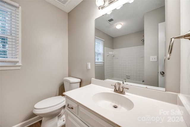 full bathroom with a textured ceiling, vanity, toilet, and tiled shower / bath