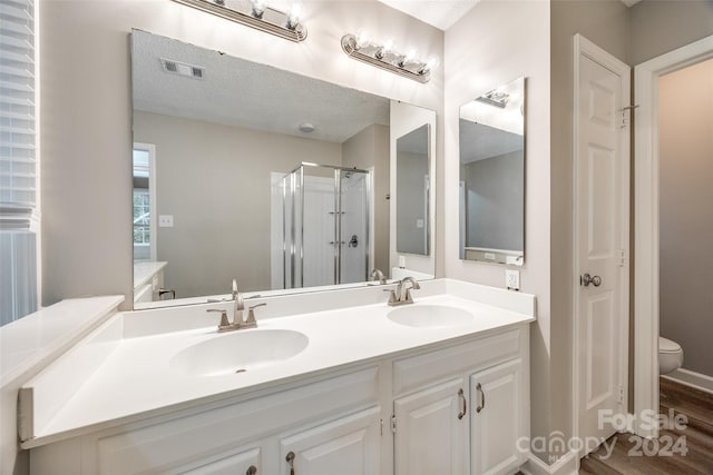 bathroom featuring vanity, a textured ceiling, toilet, and an enclosed shower