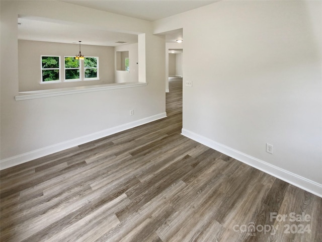 spare room with a chandelier and dark hardwood / wood-style flooring