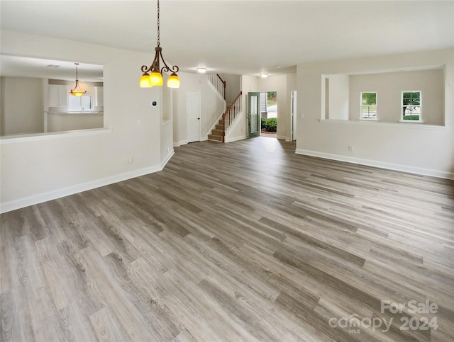 unfurnished living room with an inviting chandelier and hardwood / wood-style flooring