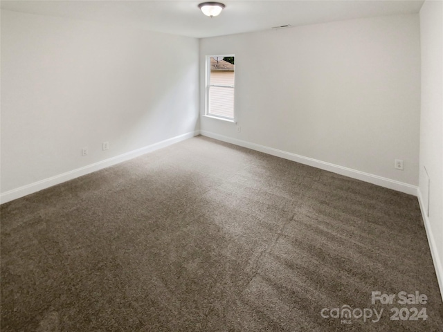 spare room with dark carpet