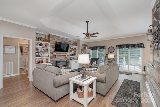 living room featuring ceiling fan, light hardwood / wood-style flooring, built in features, and a tray ceiling