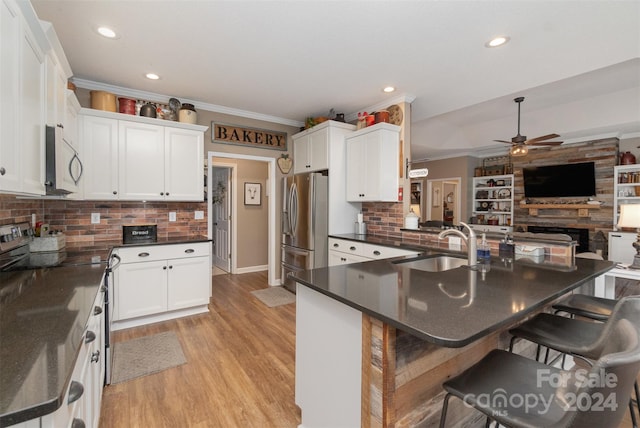 kitchen with kitchen peninsula, a breakfast bar area, ceiling fan, and stainless steel appliances