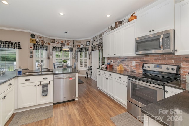 kitchen featuring stainless steel appliances, crown molding, light wood-type flooring, and sink