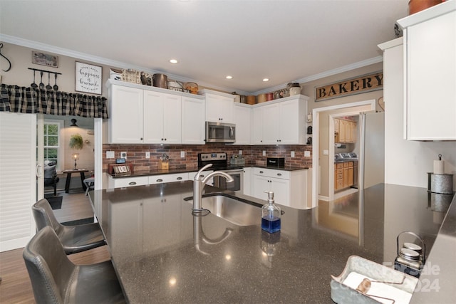 kitchen featuring appliances with stainless steel finishes, ornamental molding, sink, and white cabinets