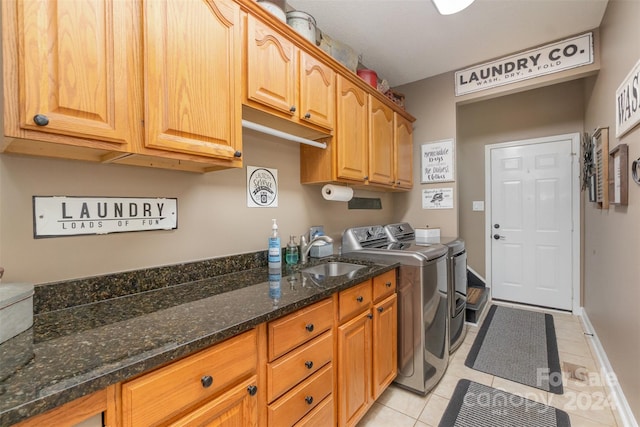 clothes washing area with washer and clothes dryer, light tile patterned floors, cabinets, and sink