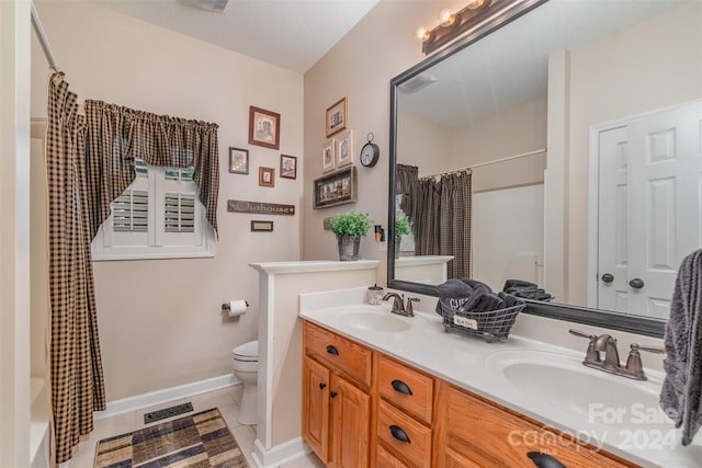 full bathroom featuring tile patterned flooring, a textured ceiling, shower / tub combo with curtain, vanity, and toilet