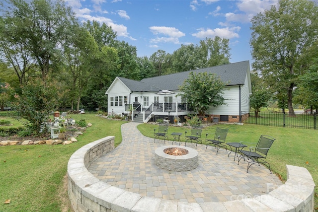 rear view of property featuring a lawn, a patio area, a deck, and a fire pit