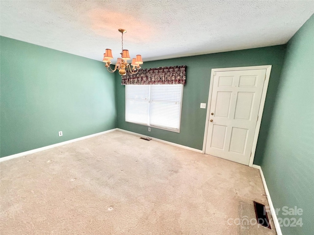 unfurnished room featuring carpet floors, a textured ceiling, and a chandelier