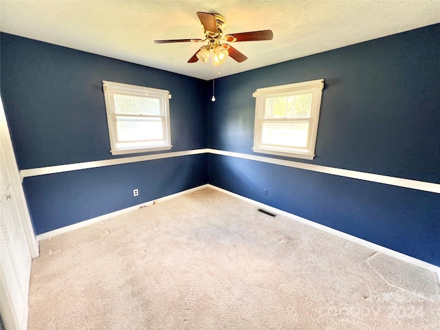 carpeted spare room featuring ceiling fan and a textured ceiling