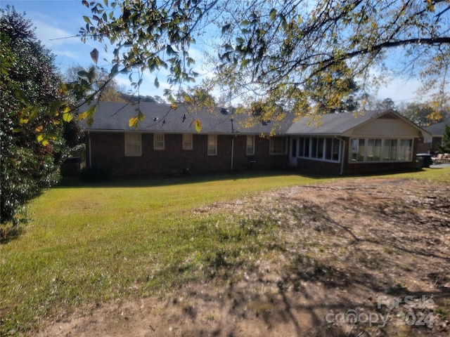 back of property with a yard and a sunroom