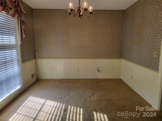 empty room with light carpet and a notable chandelier