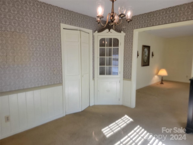 unfurnished dining area featuring a chandelier and carpet