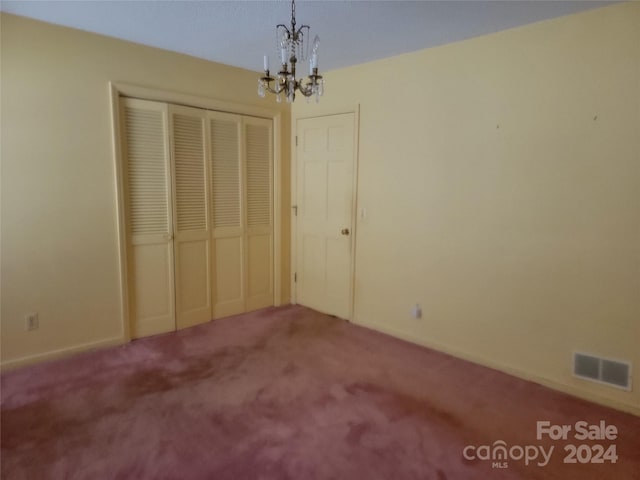 unfurnished bedroom featuring a closet, carpet, and a chandelier