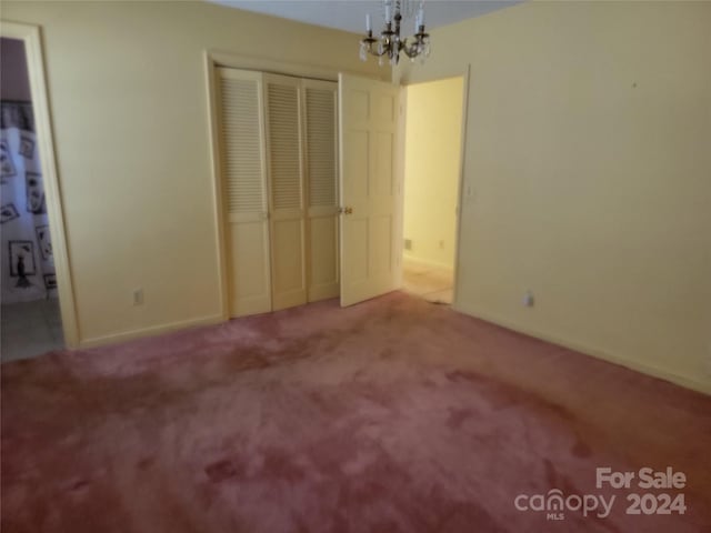 unfurnished bedroom featuring light carpet and a chandelier