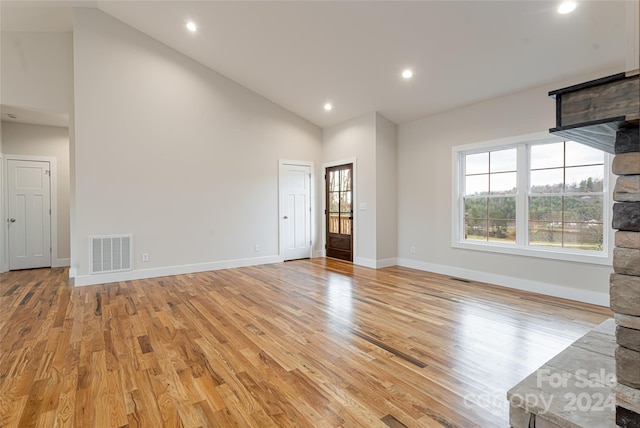 unfurnished living room with light hardwood / wood-style floors and high vaulted ceiling