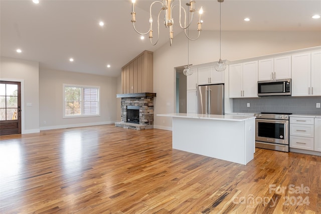 kitchen with a center island, white cabinets, light wood-type flooring, decorative light fixtures, and stainless steel appliances