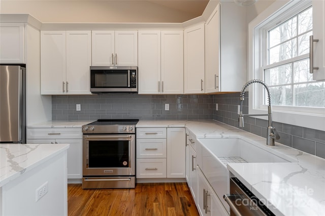 kitchen with white cabinetry, dark wood-type flooring, stainless steel appliances, and light stone counters