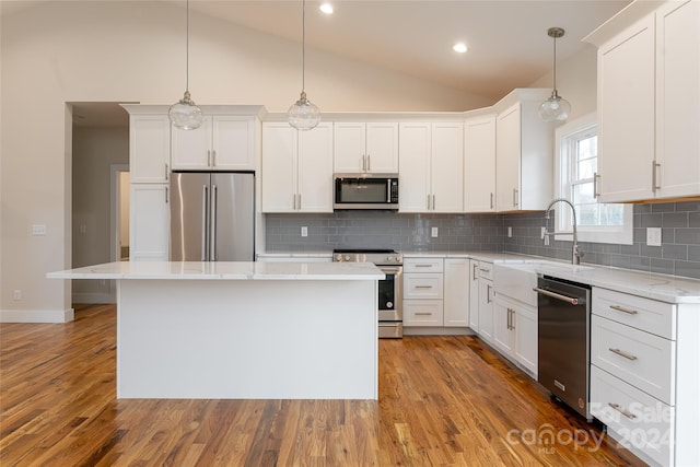 kitchen with white cabinets, stainless steel appliances, a kitchen island, and hanging light fixtures