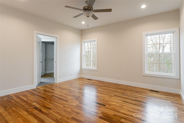 unfurnished bedroom with a spacious closet, a closet, ceiling fan, and light hardwood / wood-style floors