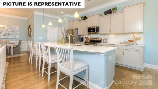 kitchen with stainless steel appliances, a kitchen island with sink, pendant lighting, and light hardwood / wood-style floors