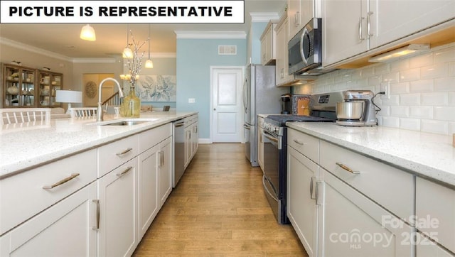 kitchen featuring stainless steel appliances, hanging light fixtures, sink, and light stone counters