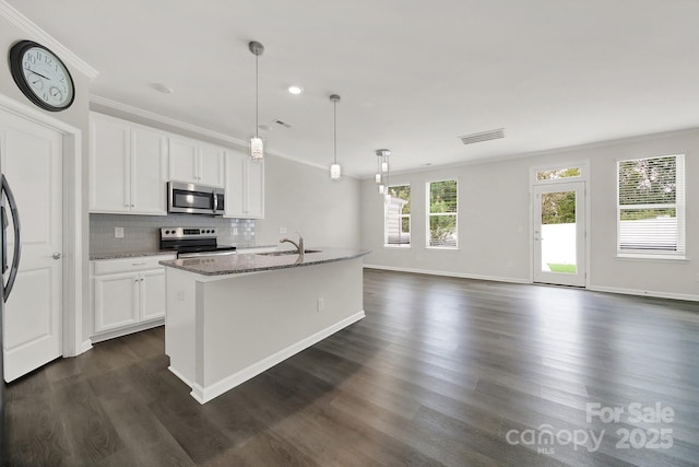 kitchen featuring white cabinets, appliances with stainless steel finishes, decorative light fixtures, an island with sink, and stone counters