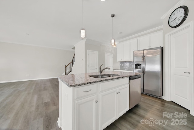 kitchen with white cabinets, appliances with stainless steel finishes, sink, a kitchen island with sink, and light stone counters