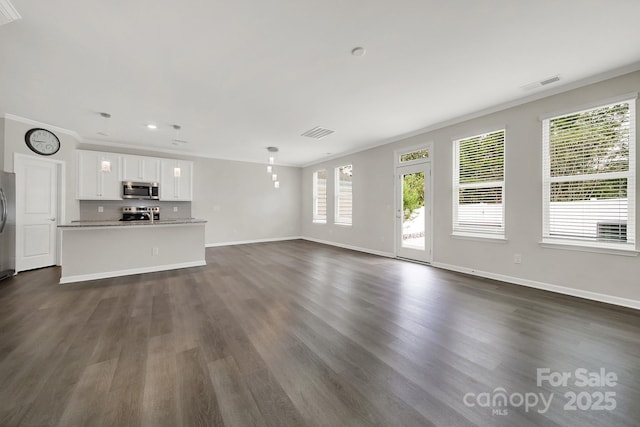 unfurnished living room with a wealth of natural light, ornamental molding, and dark hardwood / wood-style floors