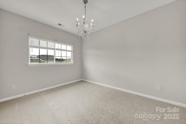 carpeted empty room with a notable chandelier