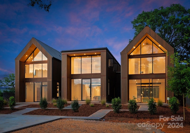 back house at dusk featuring a balcony