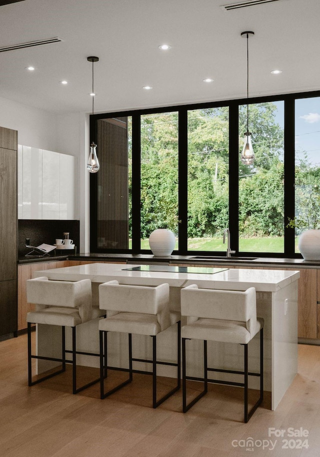 interior space with a kitchen island, light wood-type flooring, hanging light fixtures, and a healthy amount of sunlight