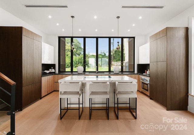 kitchen featuring a kitchen island, light wood-type flooring, decorative light fixtures, and a breakfast bar area