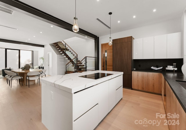 kitchen featuring light hardwood / wood-style floors, white cabinetry, decorative light fixtures, and a kitchen island