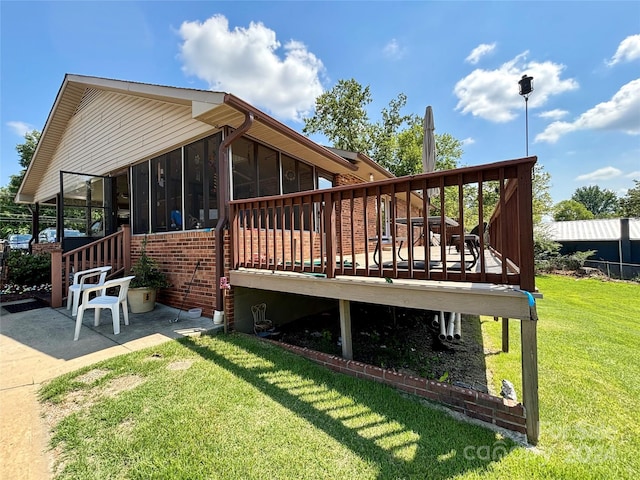 back of property with a sunroom, a patio, a deck, and a lawn