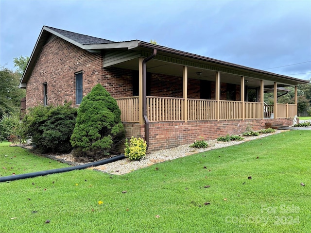 view of side of property with a yard and covered porch