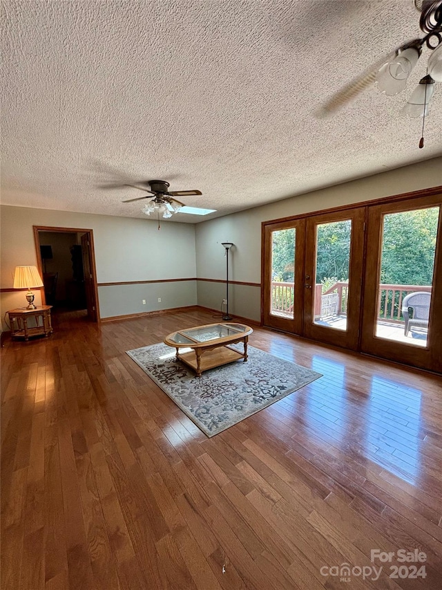 unfurnished living room with ceiling fan, hardwood / wood-style flooring, and a textured ceiling